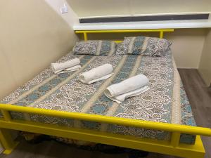 a yellow bed with two pillows and towels on it at D'Schnuggs Place in Panglao Island