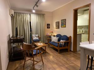 ein Wohnzimmer mit einem blauen Sofa und Stühlen in der Unterkunft Conforto e simplicidade no centro da cidade in Santana do Livramento