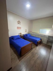 2 camas en un dormitorio con sábanas azules en Conforto e simplicidade no centro da cidade, en Santana do Livramento