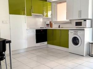 una cocina con armarios verdes y blancos y una lavadora en Appartement Bormes-les-Mimosas, 2 pièces, 5 personnes - FR-1-610-74, en Bormes-les-Mimosas