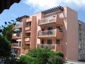un gran edificio rosa con balcones y árboles en Appartement Bormes-les-Mimosas, 2 pièces, 5 personnes - FR-1-610-74, en Bormes-les-Mimosas