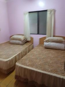 2 Betten in einem Zimmer mit Fenster in der Unterkunft Ruishi Homestay in T'ai-ping