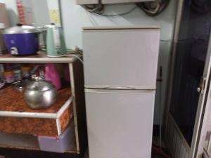 um frigorífico branco numa cozinha ao lado de uma prateleira em Ruishi Homestay em T'ai-ping
