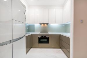 a kitchen with white cabinets and a stove at Moxy HCMC Aparts - Vinhomes Central Park, Ice Rink in Ho Chi Minh City