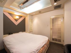 ein Schlafzimmer mit einem großen weißen Bett in einem Zimmer in der Unterkunft Tabist Hotel Rakuserina in Fuefuki