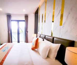 a bedroom with a bed with white sheets and pillows at Aloha Hotel Quy Nhơn in Quy Nhon