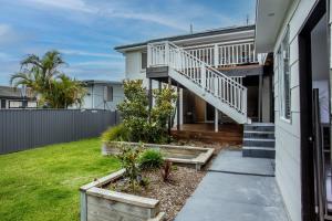 a house with a staircase and a yard at Cheerful Lakeside House-Minutes away from anywhere in Lake Munmorah