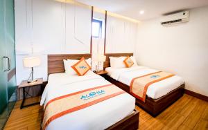 a hotel room with two beds and a window at Aloha Hotel Quy Nhơn in Quy Nhon