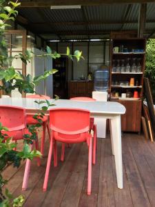 - une table blanche et des chaises rouges sur la terrasse dans l'établissement Pension Te Aroha - Te Rai, à Maatea