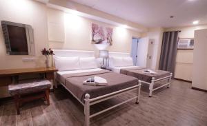 a hotel room with two beds and a desk at 1775 Adriatico Suites in Manila