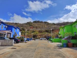 BELLA SUITE frente al Aeropuerto في Catia La Mar: موقف للسيارات مع بيوت ملونة وجبل