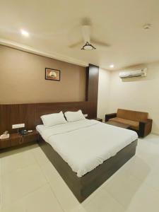 - une chambre avec un grand lit blanc et un canapé dans l'établissement Hotel Palav Palace, à Ahmedabad