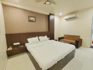 una camera con un grande letto bianco e una sedia di Hotel Palav Palace a Ahmedabad