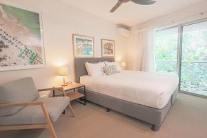 una camera da letto con un letto, una sedia e una finestra di The Cove Noosa - Apartment 19 a Noosa Heads
