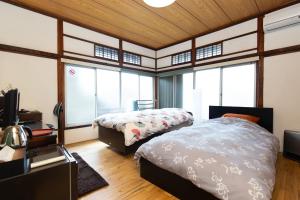 a bedroom with two beds and a tv and windows at Kitazawa Cozy House in Tokyo