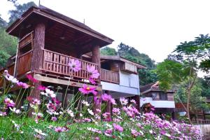 een huis met bloemen ervoor bij LANNA HOUSE บ้านลานนา เชียงดาว in Chiang Dao