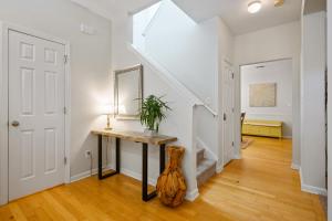 a hallway with white walls and a staircase with a table and a mirror at Spacious Serene 3BR Near LakePoint & DT Acworth in Acworth