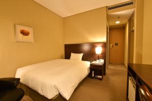 una camera d'albergo con un grande letto e una scrivania di Hotel Nikko Tsukuba a Tsukuba