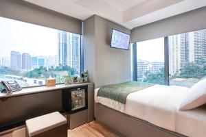 a bedroom with a bed and a desk and windows at Urbanwood Ap Lei Chau in Hong Kong