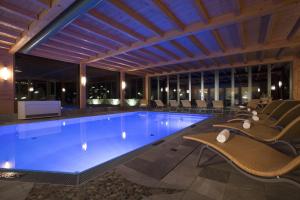 une grande piscine avec des chaises et une table dans l'établissement Wanderhotel Taurerwirt, à Kals am Großglockner