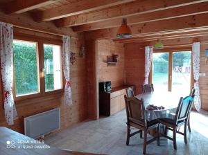 una sala da pranzo con tavolo e sedie in una cabina di Chalet Familial en Bois à 150 m de la Mer a Santec