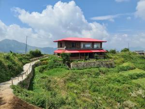 ein Haus mit rotem Dach auf einem Hügel in der Unterkunft The Rosly Estate in Kanatal