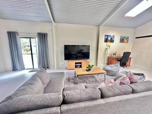 a living room with a large couch and a flat screen tv at CandE’s Guesthouse in Kingscote