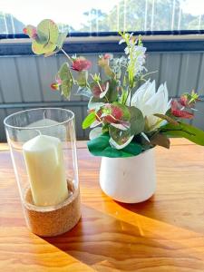 CandE’s Guesthouse في كنغزكوت: شمعة و مزهرية مع الزهور على طاولة