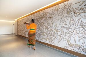 a woman standing in front of a wall with a mural at Anja Jimbaran in Jimbaran