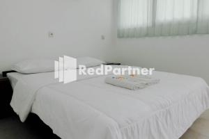 a bedroom with a white bed with white sheets and a red parameter at Ken Zong Inn Hotel in Cijaringao