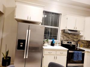 um frigorífico de aço inoxidável numa cozinha com armários brancos em House Clara em Yuba City