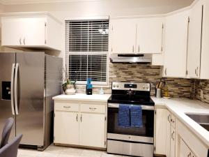 uma cozinha com armários brancos e um frigorífico de aço inoxidável em House Clara em Yuba City
