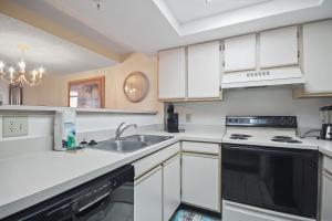 uma cozinha com armários brancos e um lavatório em Beach Colony 415 em Myrtle Beach
