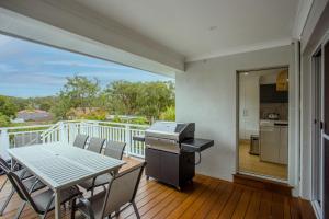 a dining room with a table and chairs on a balcony at Cheerful Lakeside House-Minutes away from anywhere in Lake Munmorah
