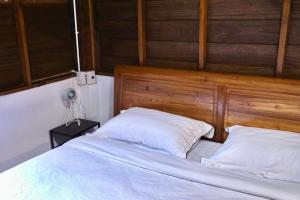 łóżko z 2 białymi poduszkami i drewnianym zagłówkiem w obiekcie LANNA HOUSE บ้านลานนา เชียงดาว w mieście Chiang Dao