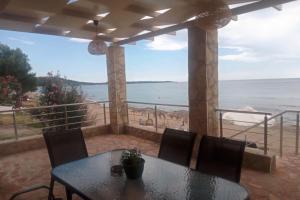 una mesa y sillas en un balcón con vistas al océano en Maritinas Stone House & Apartment On The Beach - Happy Rentals, en Katakolon