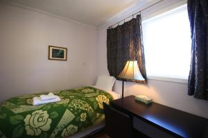 1 dormitorio con cama, escritorio y ventana en Jenny Guest House en Yellowknife
