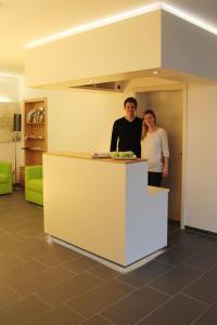 a man and woman standing at a counter in a room at Hotel Knorz in Zirndorf
