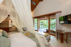 a room with a bed and a tv and a table at Jannata Resort and Spa in Ubud