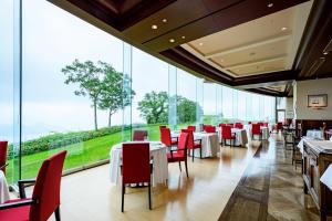 a restaurant with tables and red chairs and large windows at The Windsor Hotel TOYA Vignette Collection in Lake Toya +162 photos