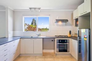 uma cozinha com armários brancos e uma janela em Bold Beauty - Paraparaumu Upstairs Holiday Unit em Paraparaumu