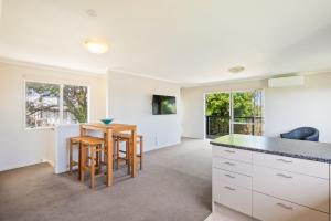 a kitchen with white cabinets and a table and chairs at Bold Beauty - Paraparaumu Upstairs Holiday Unit in Paraparaumu