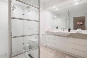 un bagno bianco con lavandino e specchio di The Cove Noosa - Apartment 8 a Noosa Heads