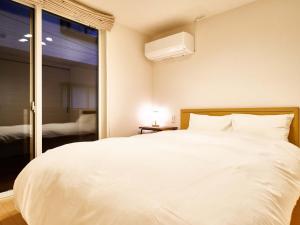 1 dormitorio con 1 cama blanca grande y ventana en Rakuten STAY HOUSE x WILL STYLE Saga Imari 101, en Imari