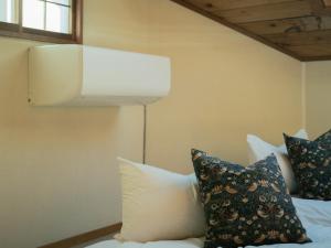 una camera da letto con letto, cuscini e lampada di Cottage Snowhills Hakuba a Hakuba