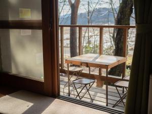 einen Balkon mit einem Tisch und Stühlen auf einer Veranda in der Unterkunft Cottage Snowhills Hakuba in Hakuba
