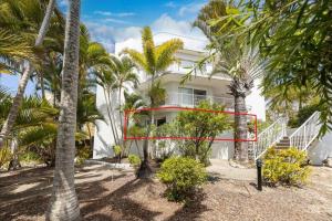 a white building with palm trees in front of it at Coolum Sands Beachside Apartment in Coolum Beach