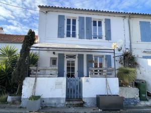 Biały dom z niebieskimi okiennicami i bramą w obiekcie Maison calme avec terrasse à Saint-Denis-d'Oléron - 5 pers, proche plage et piste cyclable - FR-1-246A-205 w mieście Saint-Denis-dʼOléron
