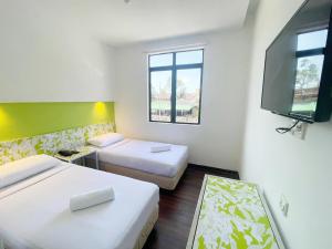 a room with two beds and a flat screen tv at Citin Langkawi by Compass Hospitality in Kuah