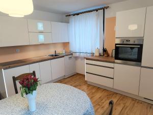 a kitchen with white cabinets and a table with a vase of flowers at Kranjska gora balcony apartment in Kranjska Gora